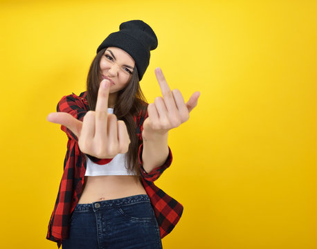 Hipster girl in jeans, checked shirt and hat showing middle fing