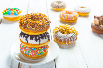 Collection of tasty donuts on white wooden board