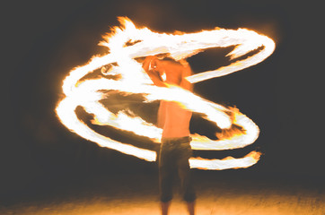 blurry focus a man rotating fireballs on the beach. Night light and have noise