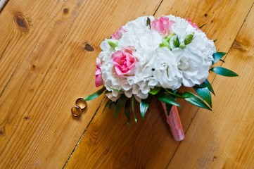 Wedding bouquet with rings at wooden background