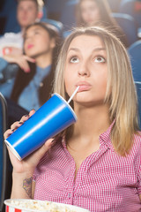 Onscreen action. Beautiful young female drinking her beverage watching movie at the cinema