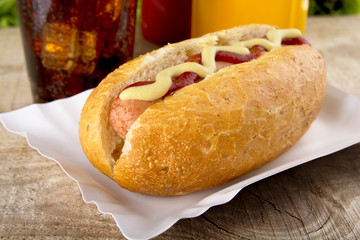 Hotdog with ketchup and mustard with cola on the wooden plank