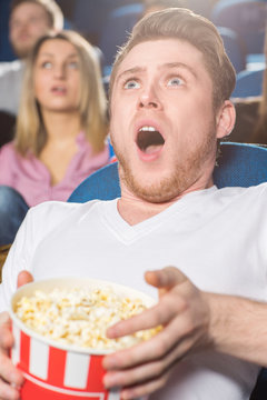 This came unexpectedly! Shot of a young man looking shocked watching movies at the local movie theatre