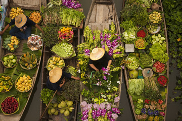 Aerial view of a floating market on a canal in Bangkok, local boats laden with fresh food, moored close together. 
