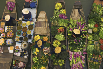 Aerial view of a floating market on a canal in Bangkok, local boats laden with fresh food, moored close together.
