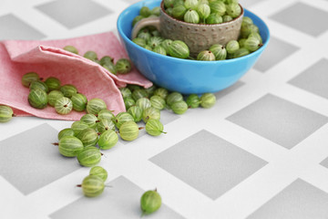 Gooseberries with cup and bowl on table