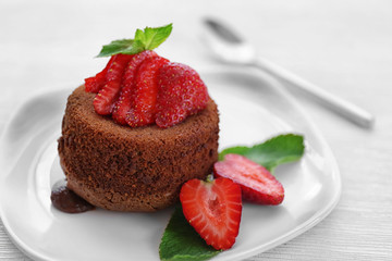 Tasty chocolate fondant with strawberries on white plate, closeup