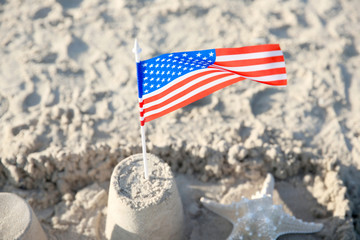 Naklejka premium Sand castle with American flag on beach