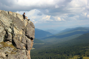 Hiker with backpack sitting on top off high rocks. Tourism conce