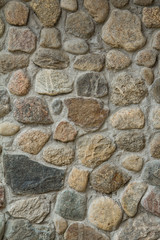 The walls are constructed of stone, concrete and gravel. Abstract pattern. Vertical stone background. Stone texture