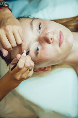 Obraz na płótnie Canvas The workflow in a beauty salon girl plucked eyebrows. Tweezers.