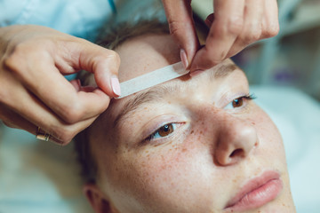 Beautiful young woman getting a face treatment at beauty salon. Adhesive plaster