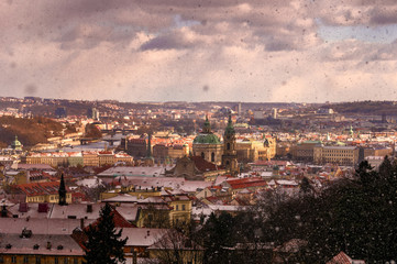 Fototapeta na wymiar Amazing Gothic church of Our Lady and St. Nicolas church during winter day with heavy snow storm and sunrays peeping through clouds, Prague, Czech republic