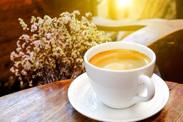 White coffee cup with dry flower on wooden table.Focus coffee wi