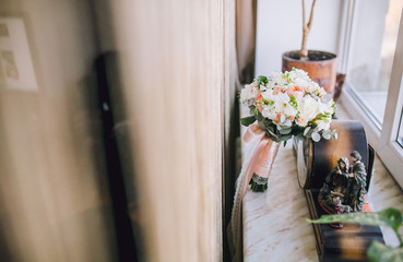 Detail of wedding bouquet standing near the window and old clock.
