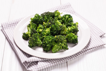 Bunch of fresh green broccoli on brown plate over wooden background