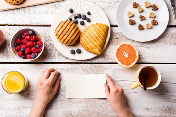 Hand of woman holding empty paper note. Breakfast meal.