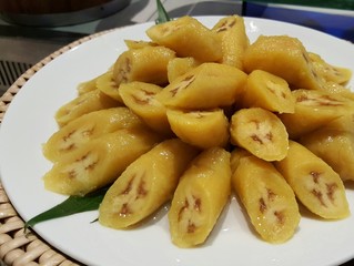 Sweet boiled banana dessert with coconut milk on white plate for local Thai snack background