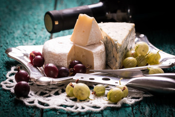 Composition of cheese, berries, bottles and glasses of wine on a wooden table