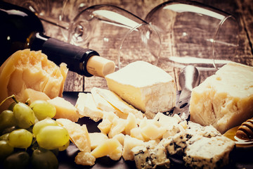 Composition of cheese, berries, bottles and glasses of wine on a wooden table