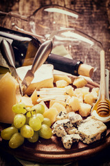 Composition of cheese, berries, bottles and glasses of wine on a wooden table