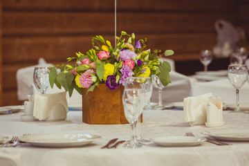 Fototapeta na wymiar flower composition in wooden vase on the served table in the restaurant. Wedding dinner