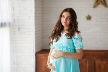 Young pregnant woman touching her belly with hands