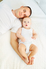 Top view of a father and baby. Dad and son baby lying on a white