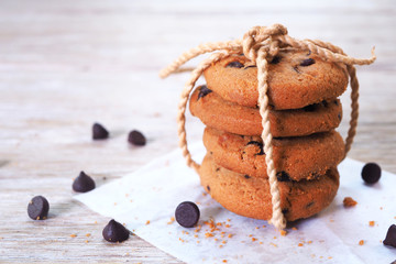 A stack of four chocolate chip cookies on waxed paper.
