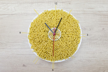 clock on a bowl fideua and stars of Italian pasta

