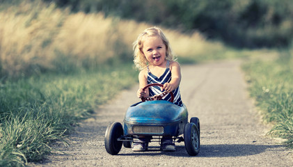 Spazierfahrt mit dem Tretauto, kleines Mädchen spielt draußen