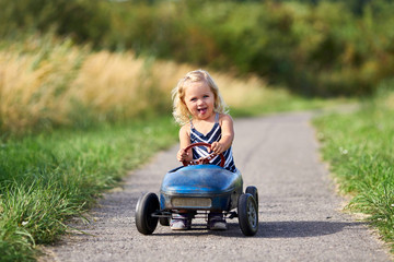 Tretauto fahren - kleines Mädchen mit Retro Blechauto