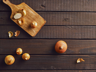 Fresh onions on a rustic wooden table prepared for cooking. Top view. Free copy space.