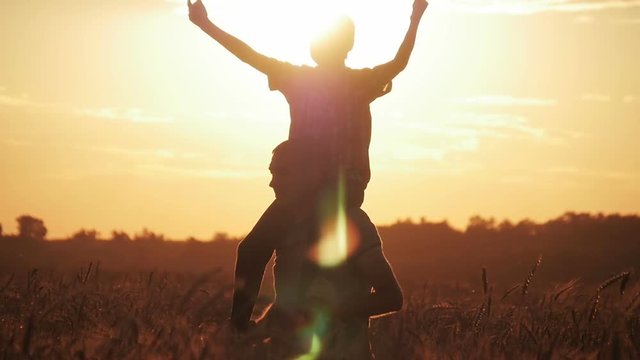 Happy dad and son going in the wheat field. Wheat field at sunset