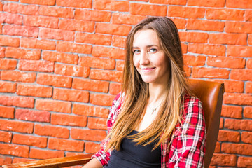 beautiful smart woman sits on chair near brick wall