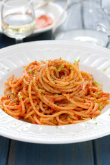 spaghetti with sauce on white plate on blue wooden background