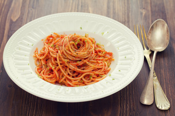 spaghetti with sauce on white plate on brown wooden background