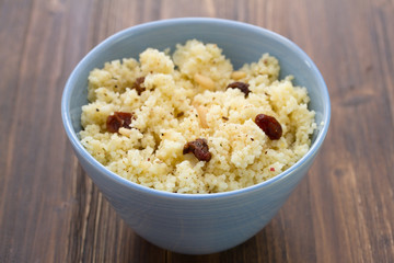 couscous with dry fruits on blue bowl on wooden background