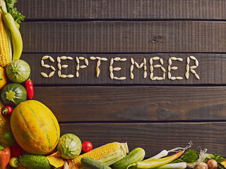 Fresh ripe autumn vegetables and herbs on garden table. Autumn background. Top view with copy space. Word september in English written of pumpkin seeds. .