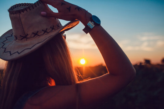 Girl in a cowboy hat in a sunflower field. Sunset