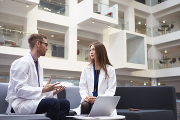 Two Doctors Having Meeting In Hospital Reception Area