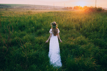 Young girl in a white dress in the meadow. Woman in a beautiful long dress posing on a meadow. Stunning bride in a wedding dress