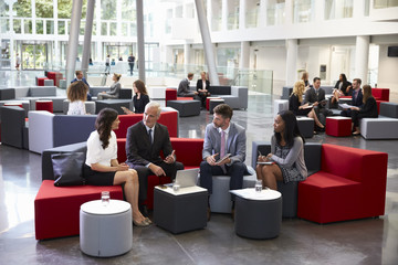 Businesspeople Meeting In Busy Lobby Of Modern Office