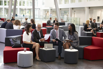 Businesspeople Meeting In Busy Lobby Of Modern Office