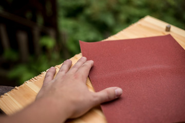Hand und Schleifpapier auf Holzplatte