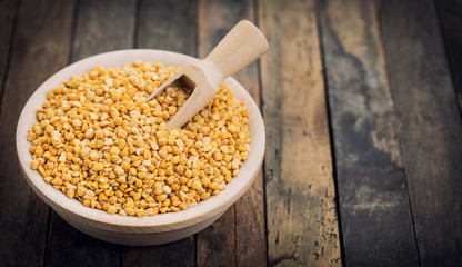 Uncooked yellow lentils in the wooden bowl