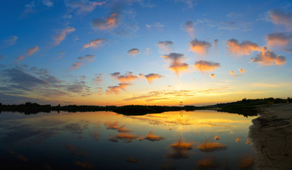 Obraz premium Clouds fly over the water at sunset.