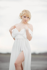 Portrait of romantic blond woman in long white dress