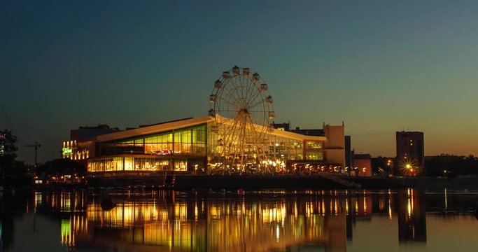 Ferris wheel reflected in water of lake at night