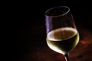 Chilled dry white wine in the glass, vintage wooden background,